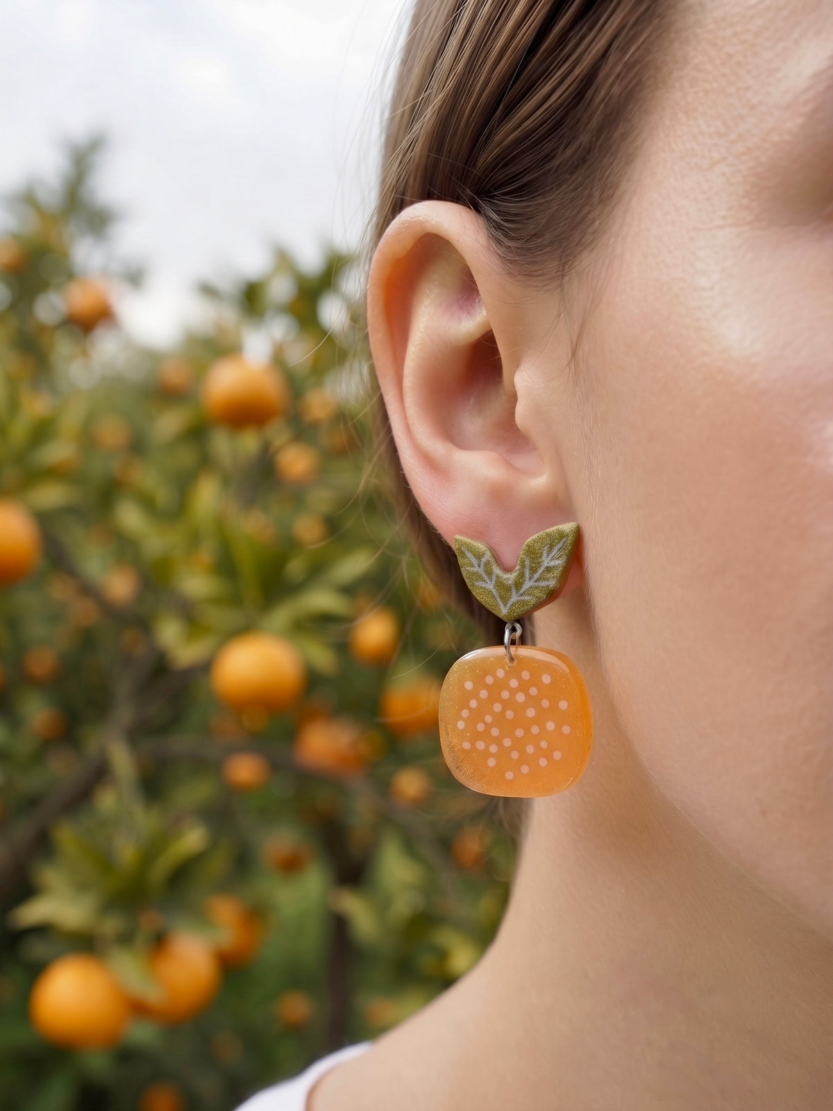 Modelo luciendo pendientes mandarina Terreta con naranjos de fondo